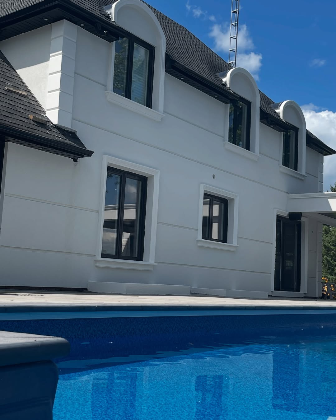 White stucco home with pool and dormer windows
